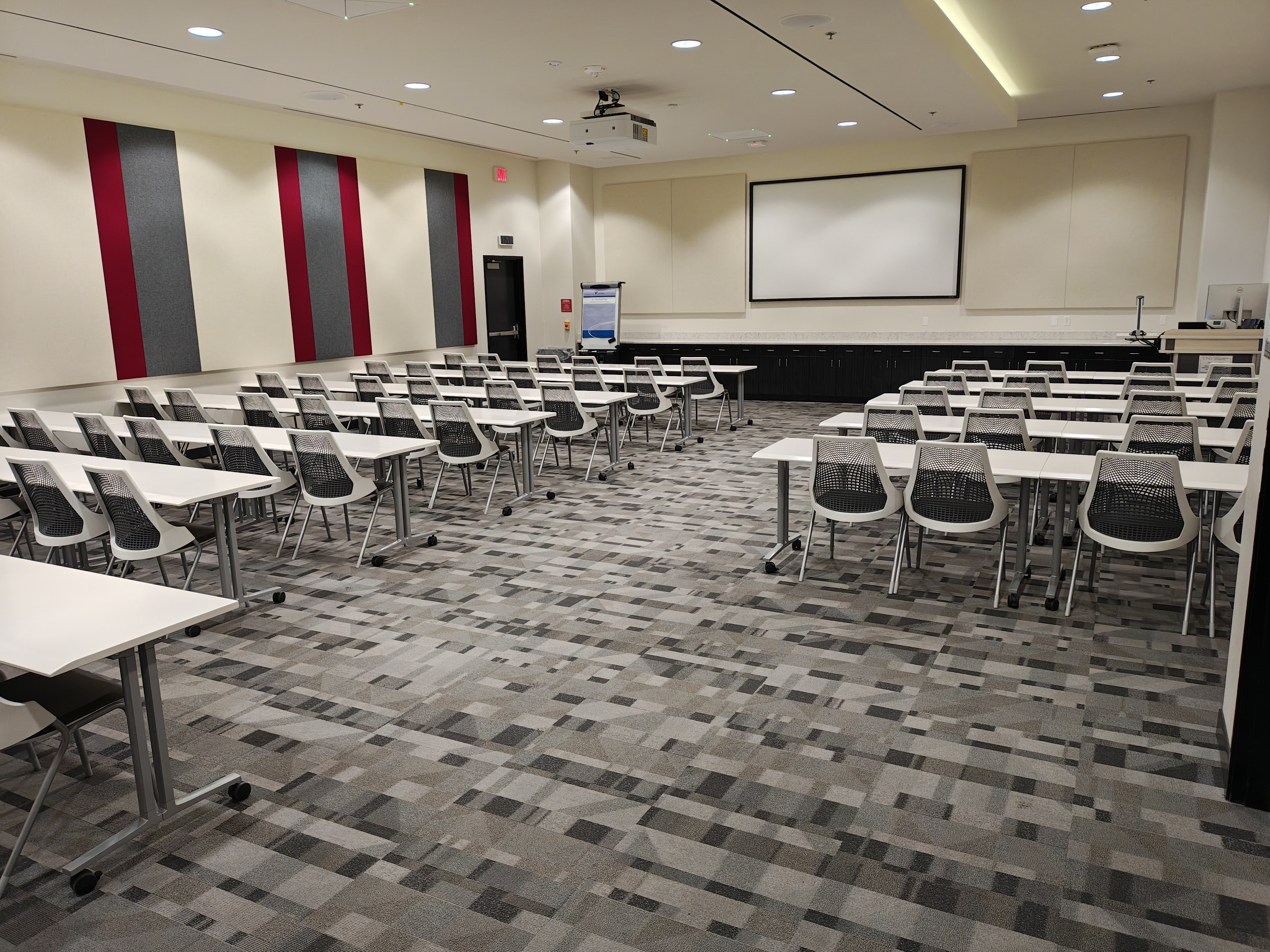 Empty classroom with rows of chairs and tables and a projector screen
