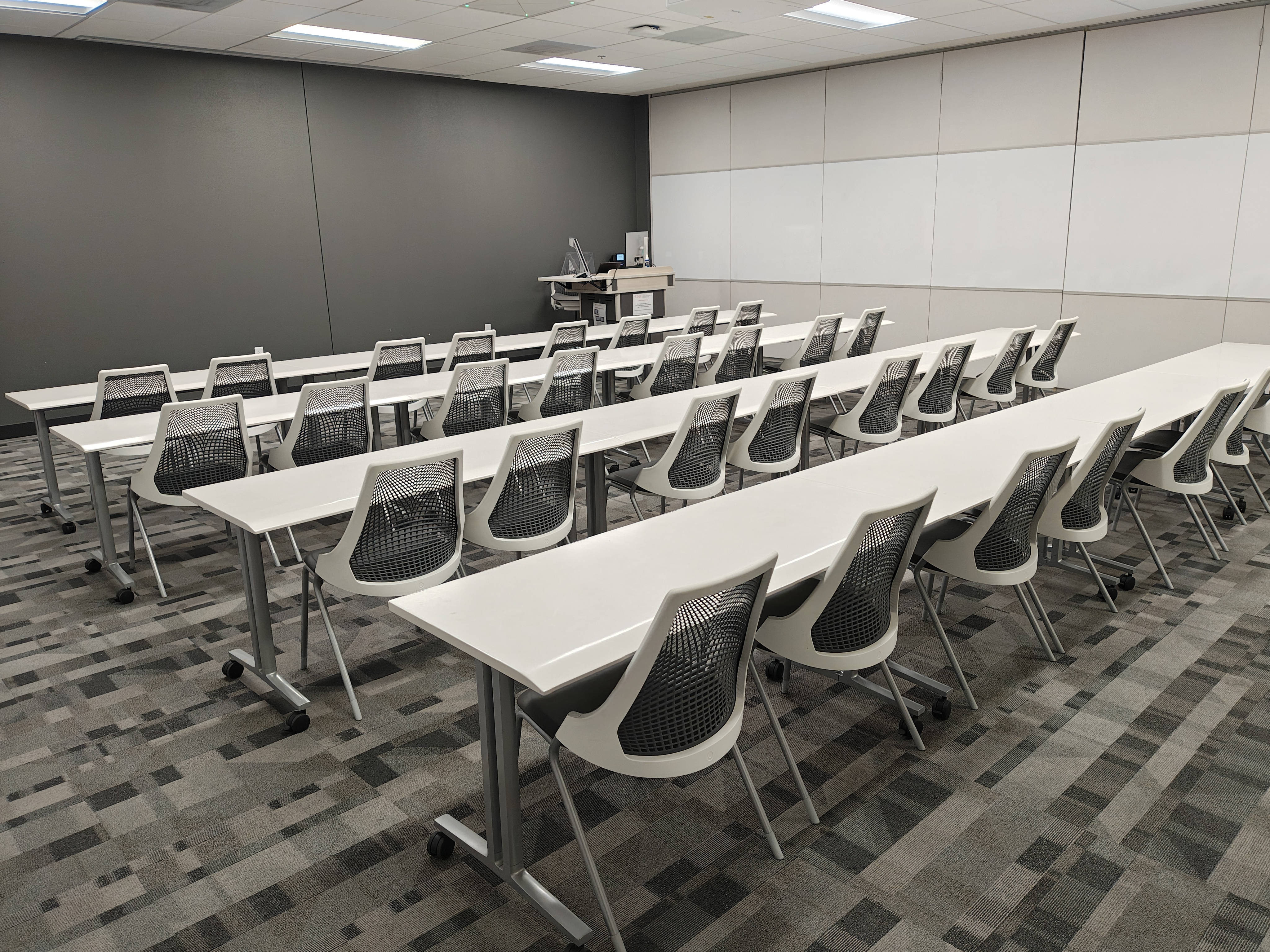 Empty classroom with rows of chairs and tables and a lectern 